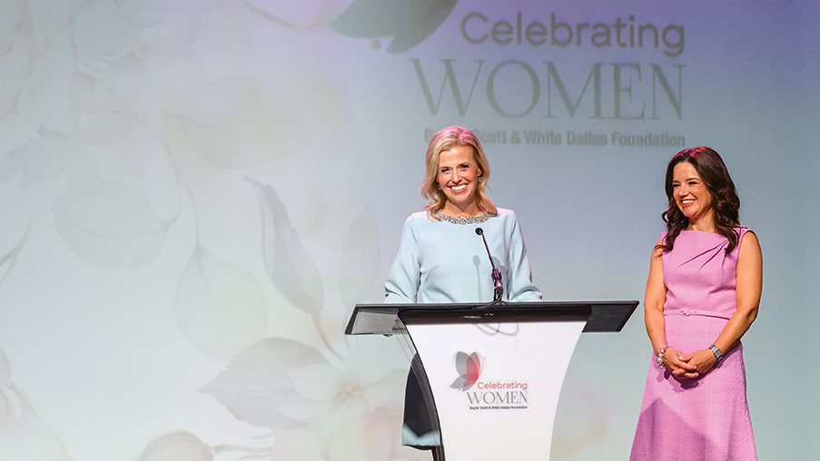 Two women on stage at a ‘Celebrating Women’ event hosted by Baylor Scott & White Dallas Foundation, with one speaking at a podium and the other standing beside her.