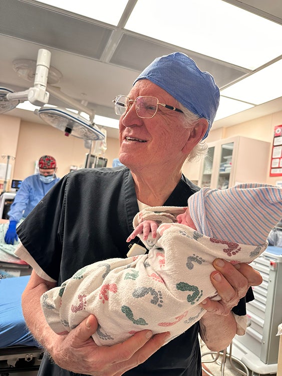 Photo of Dr. Gunby holding a newborn