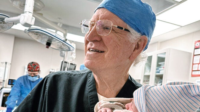 Dr. Robert T. Gunby Jr. holding a newborn baby during his final delivery before retirement.
